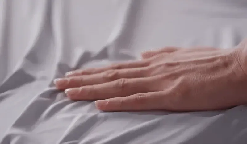 up close clip of hand moving over soft bedgear sheets.