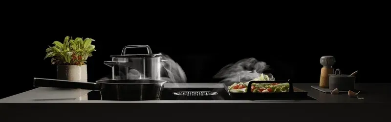steam is being pulled into the dowdraft vent of the cooktop