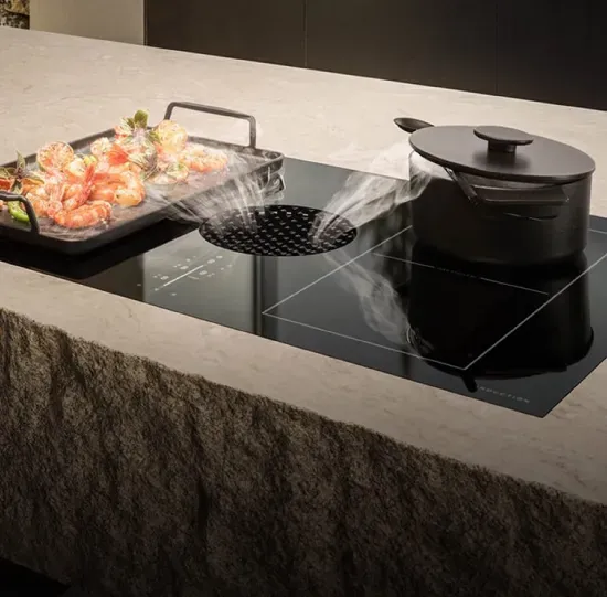 Black glass induction cooktop with a built-in circular downdraft vent at the center, drawing in steam from cookware; touch controls, flush-mounted in a stone countertop.