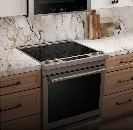 Stainless steel slide-in electric range with front controls and a smooth black glass cooktop with multiple heating zones, installed flush between base cabinets under a stone countertop and backsplash.