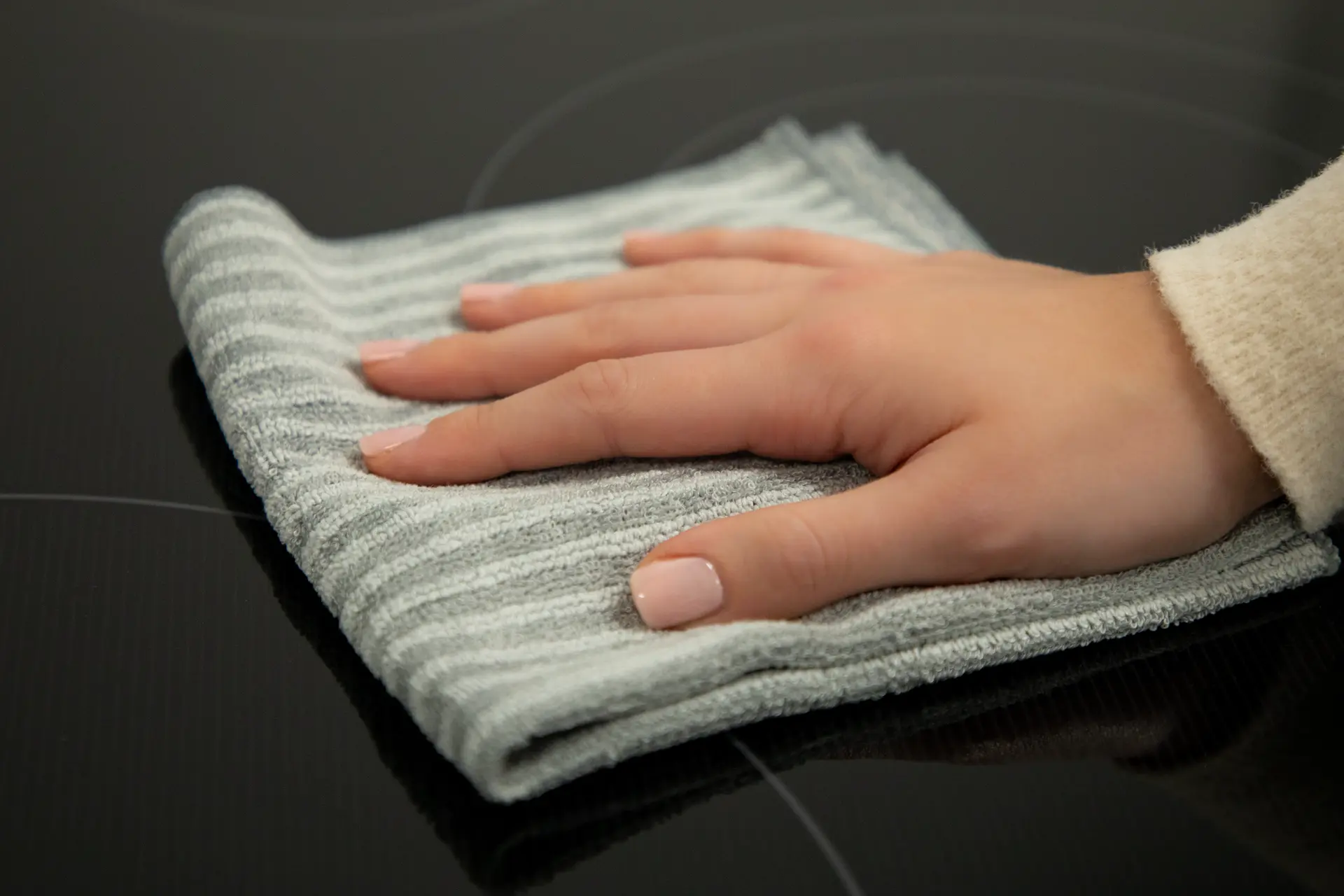 A woman's hand wiping a radiant cooktop