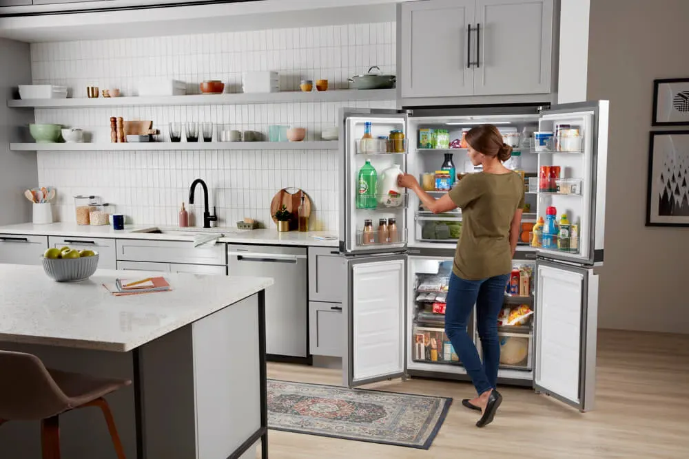 whirlpool refrigerator open, with woman sorting items inside