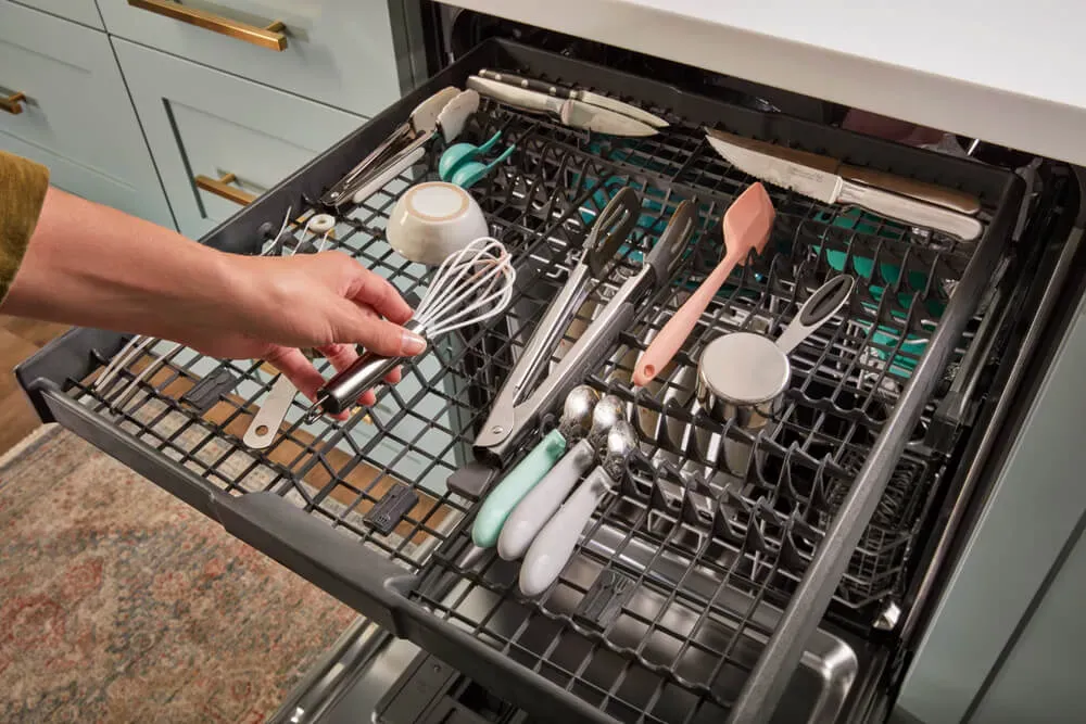 whirlpool dishwasher open with cooking utensils inside
