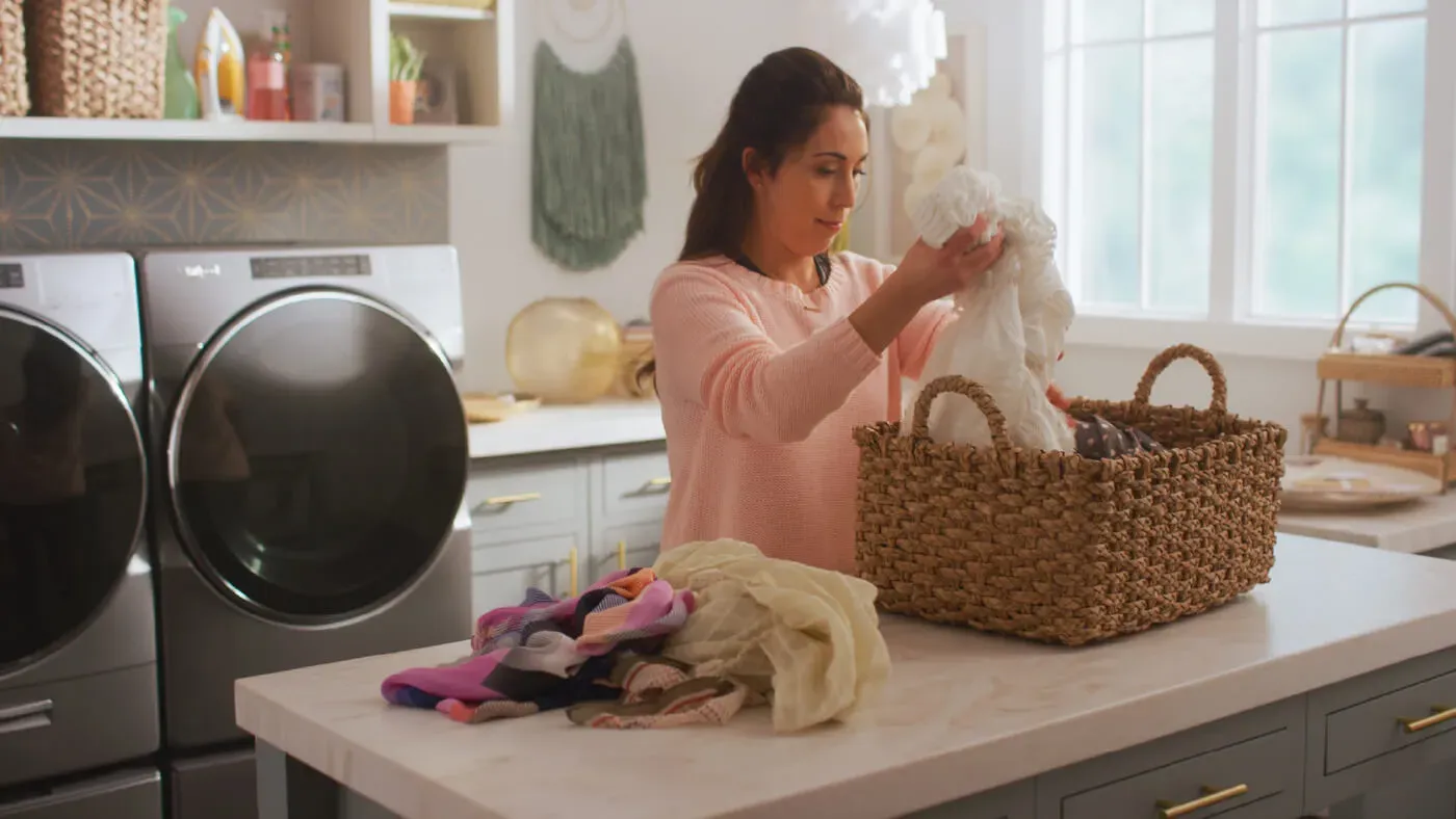 woman sorting laundry in a laundry room with whirlpool washer and dryer in background