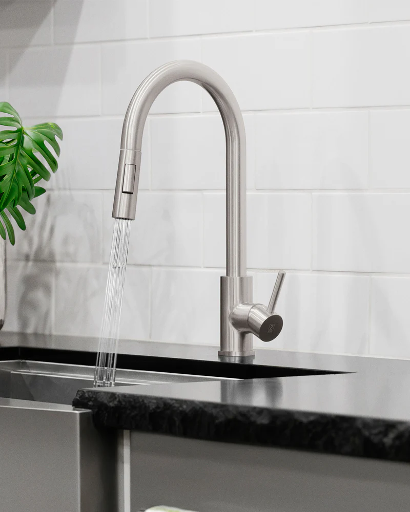 Modern kitchen faucet with water flowing into a sink against a tiled wall.