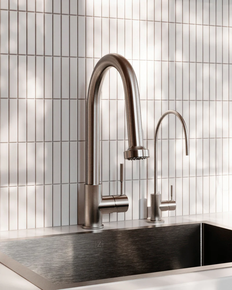 Modern kitchen faucet and sink with tiled wall background.