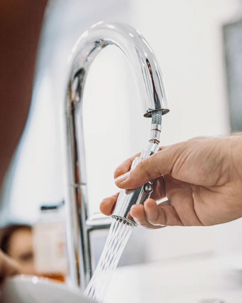 Person adjusting a faucet with water flowing.