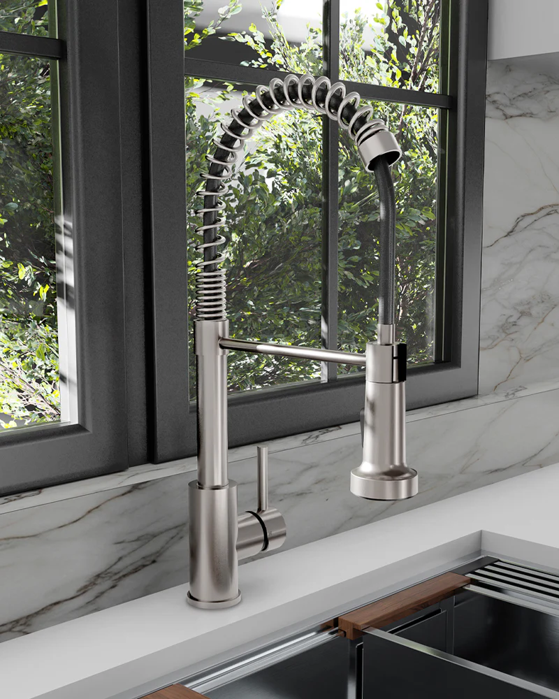 Modern kitchen faucet with a flexible spray head in front of a window with a view of greenery.
