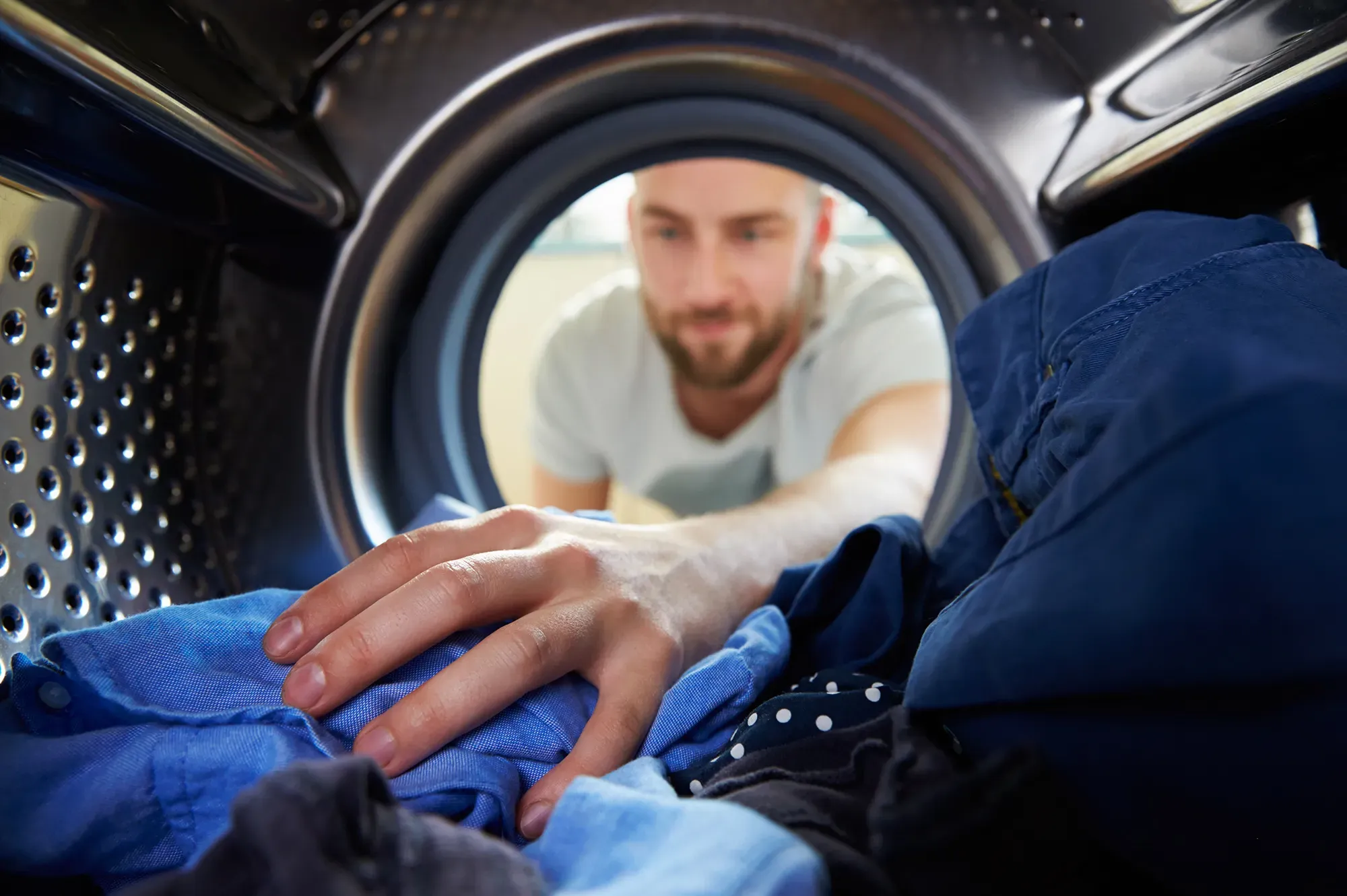 man reaches into washing machine