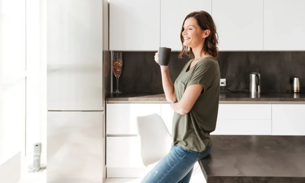 Happy woman having a drink in the kitchen