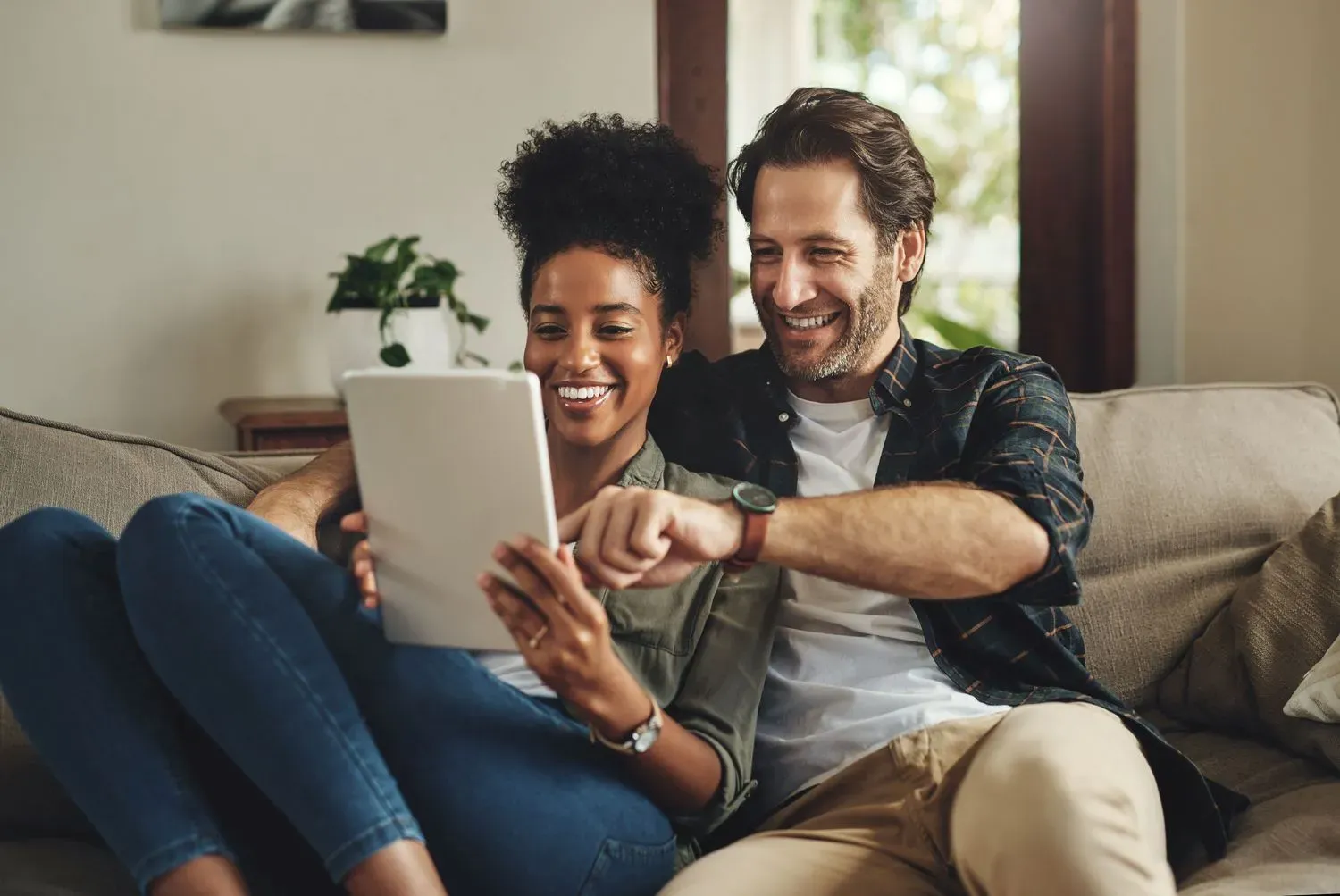 Couple sitting on a sofa browsing current offers together on a tablet