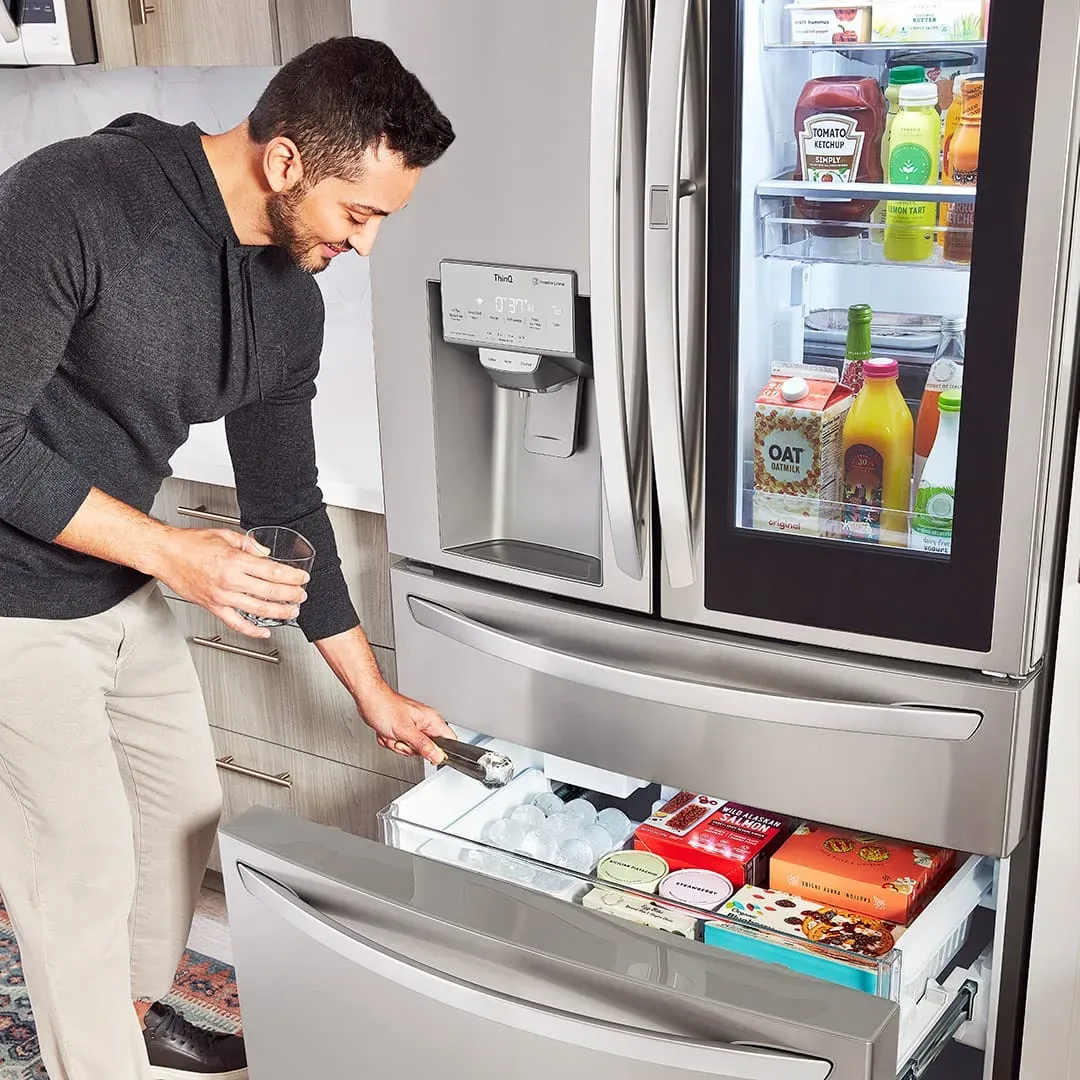 guy crouched down getting ice out of the bottom freezer