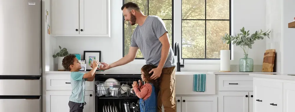 man and two kids unloading the dishwasher image