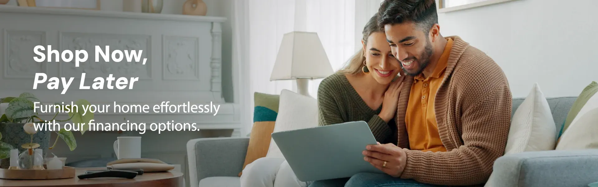 A young couple sitting on their couch at home in St. Louis, looking over a laptop discussing financing options.