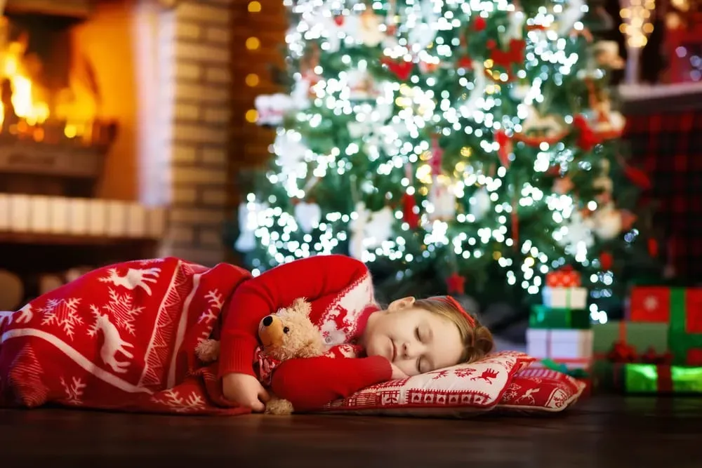 Child-asleep-on-the-floor-beneath-Christmas-tree