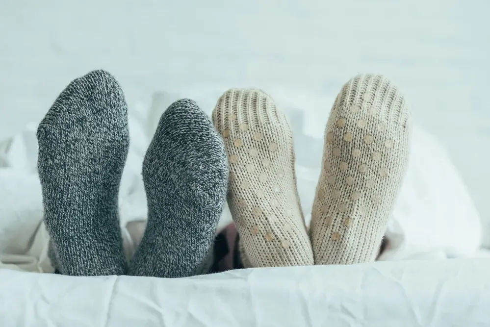 Close-up-of-couples-feet-in-knit-socks-in-bed