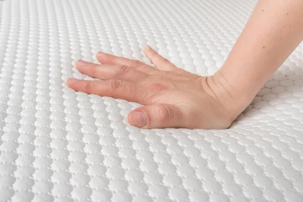 Close-up-of-hand-pressing-against-mattress