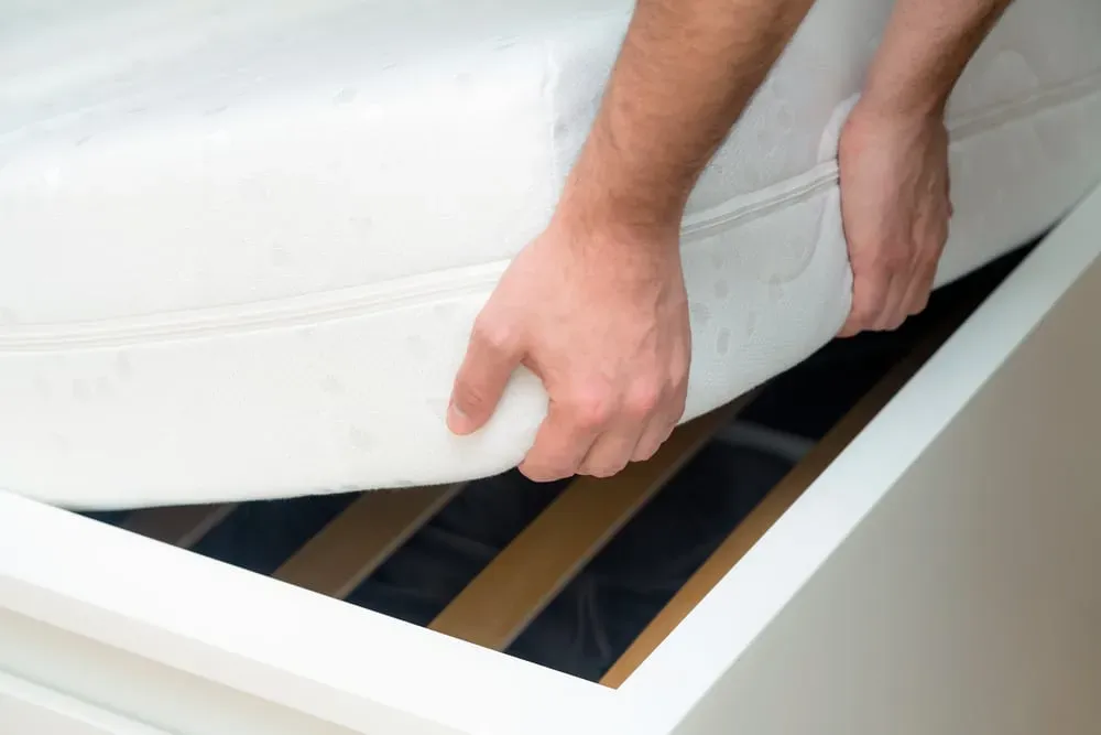 Close-up-of-person-lifting-corner-of-mattress