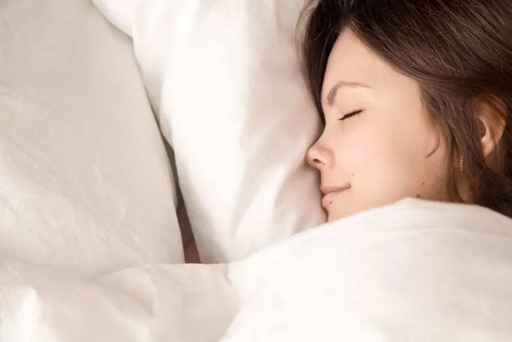 Close-up-of-young-woman-in-bed-eyes-closed-smiling