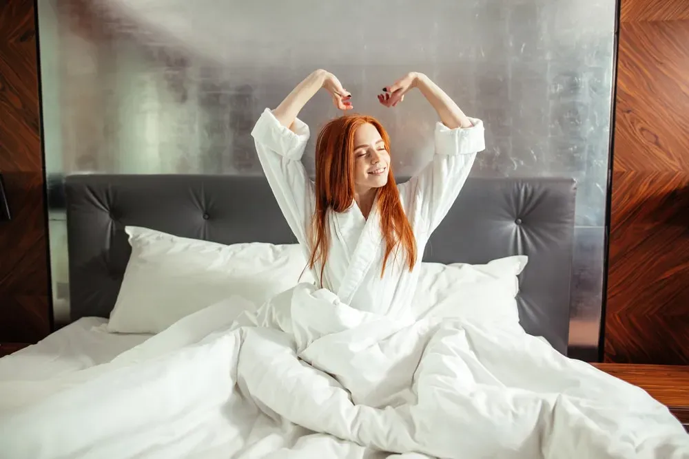 Relaxed-woman-stretching-arms-while-sitting-in-bed
