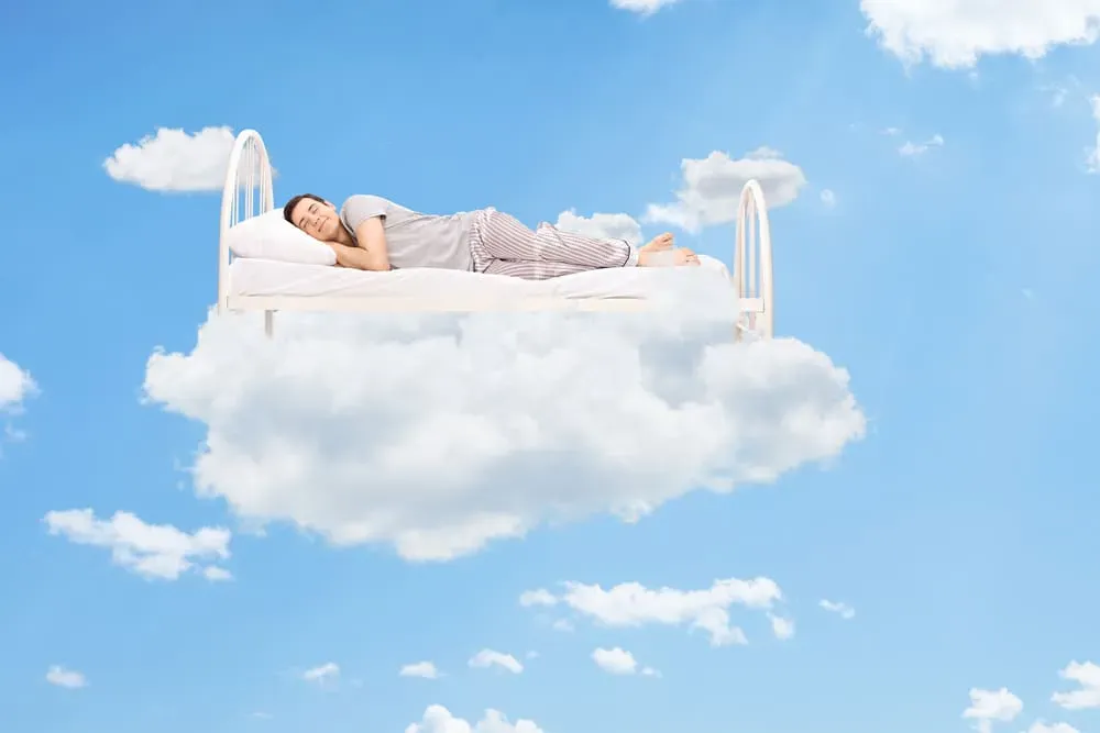 Smiling-man-sleeping-on-bed-made-of-clouds-in-the-sky