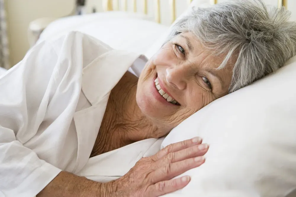 Smiling-senior-woman-lying-on-side-in-bed