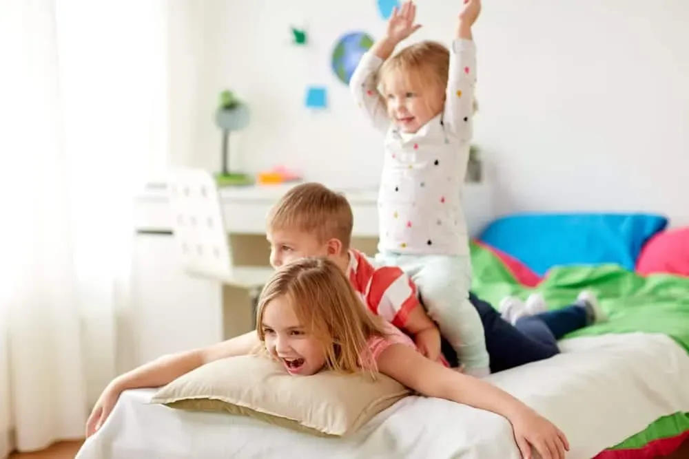 Three-happy-young-kids-playing-on-bed