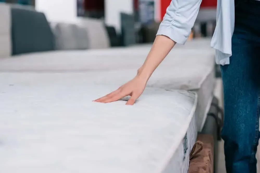 Womans-hand-touching-mattress-at-a-mattress-store