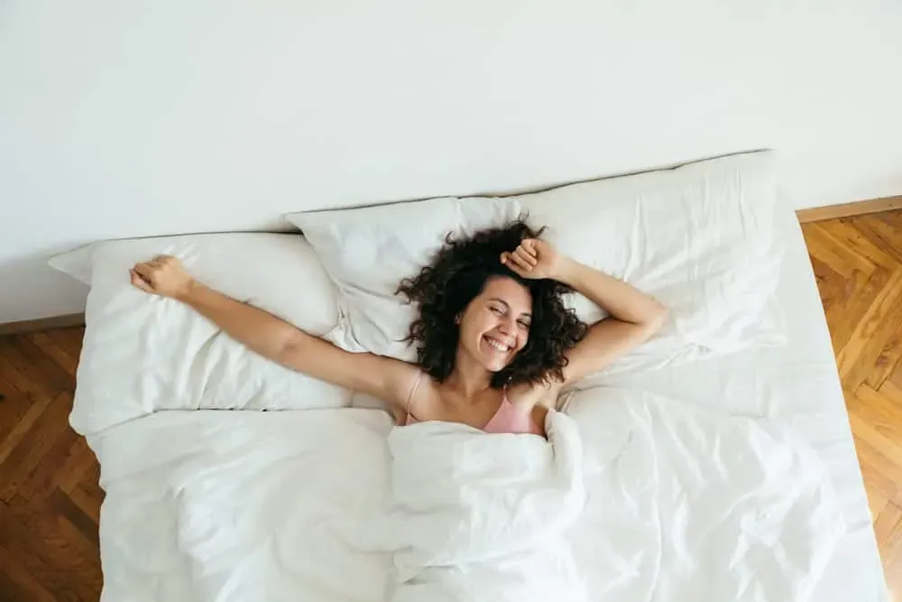 Young-woman-smiling-and-stretching-in-bed