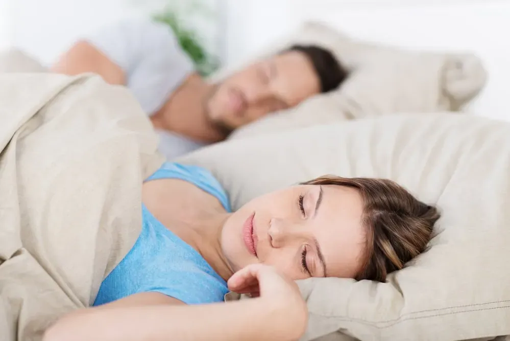 Young couple sleeping peacefully in bed, focus on woman's face