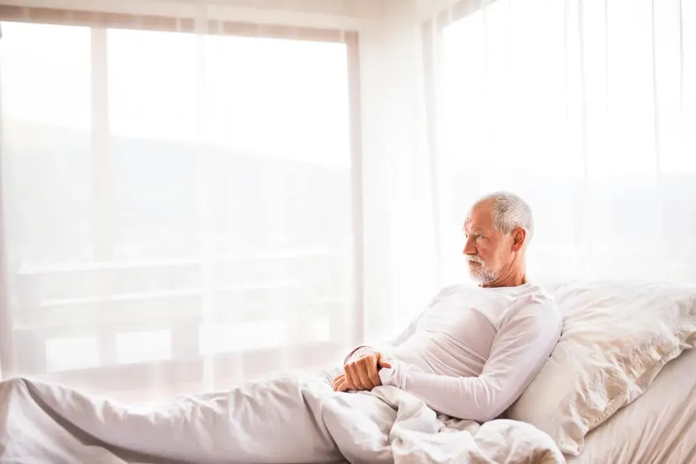 Older man lying on adjustable bed at home