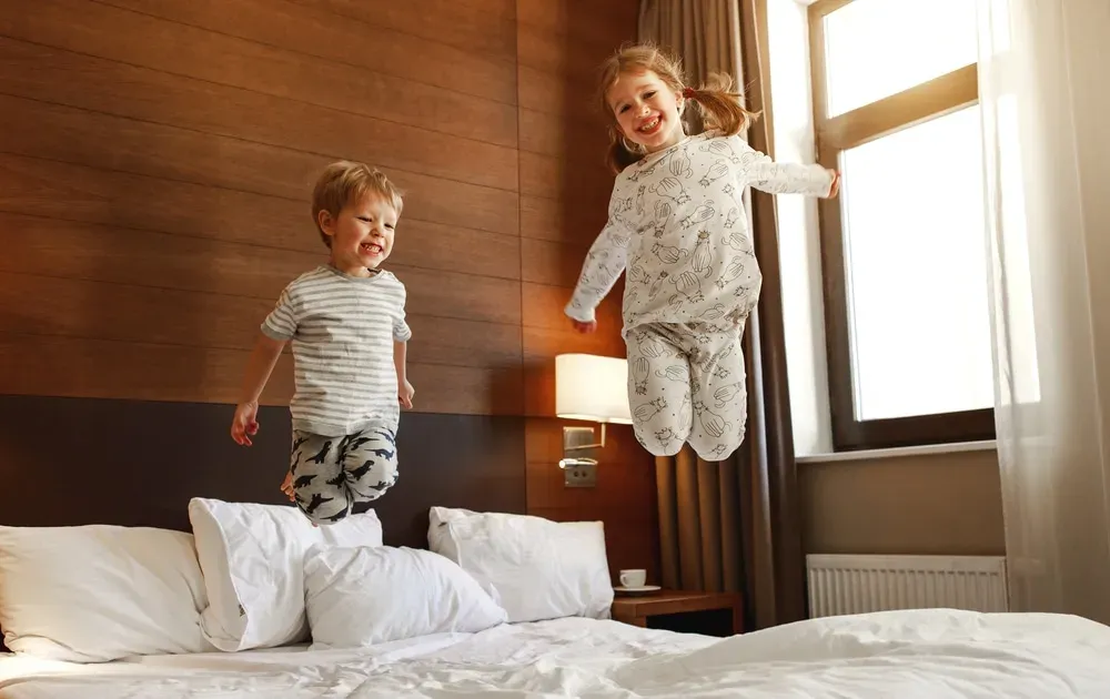 Two happy kids jumping on the bed