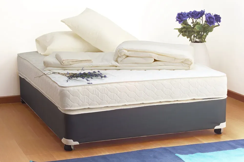 Bare mattress, pillows and blanket on top, flowers