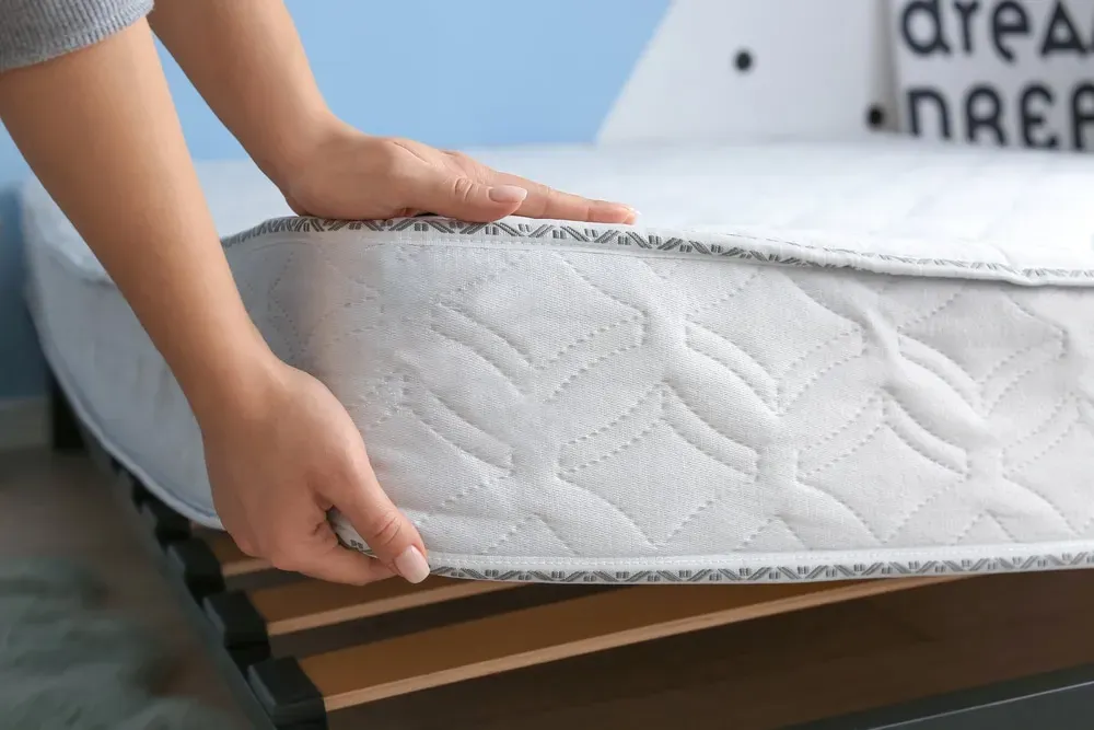 Woman lifting corner of mattress, close-up