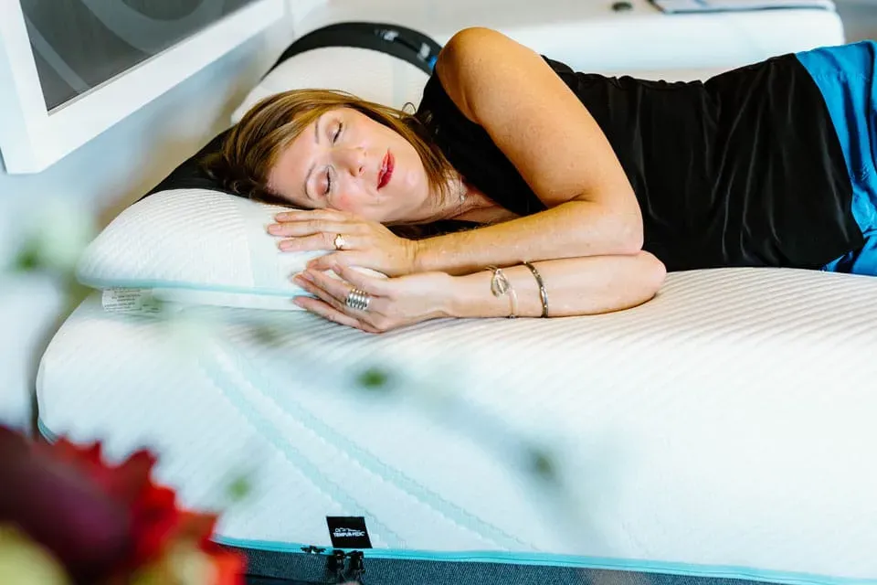 a woman lying on her side, sleeping, with arms bent in front of her torso