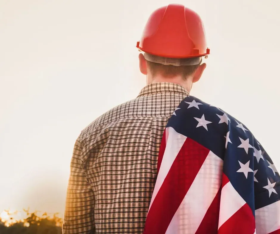 view of a man wearing a hard hat with a flag draped over his shoulder