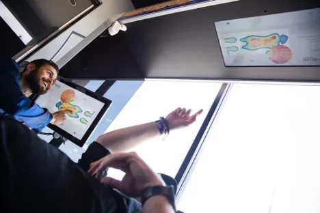 man pointing at screen laying on mattress