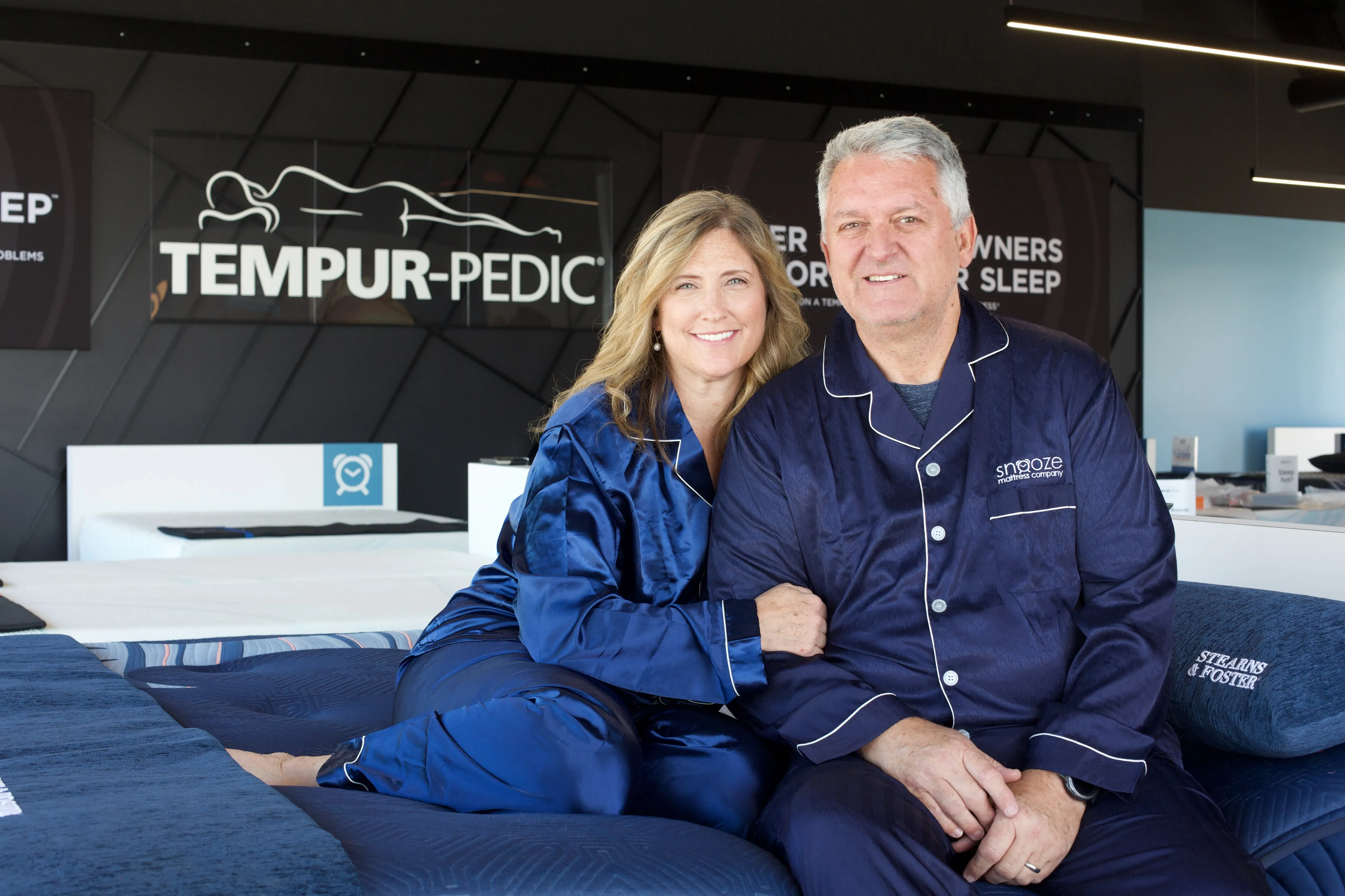 couple sitting on bed at snooze mattress company pleasant garden location Utah