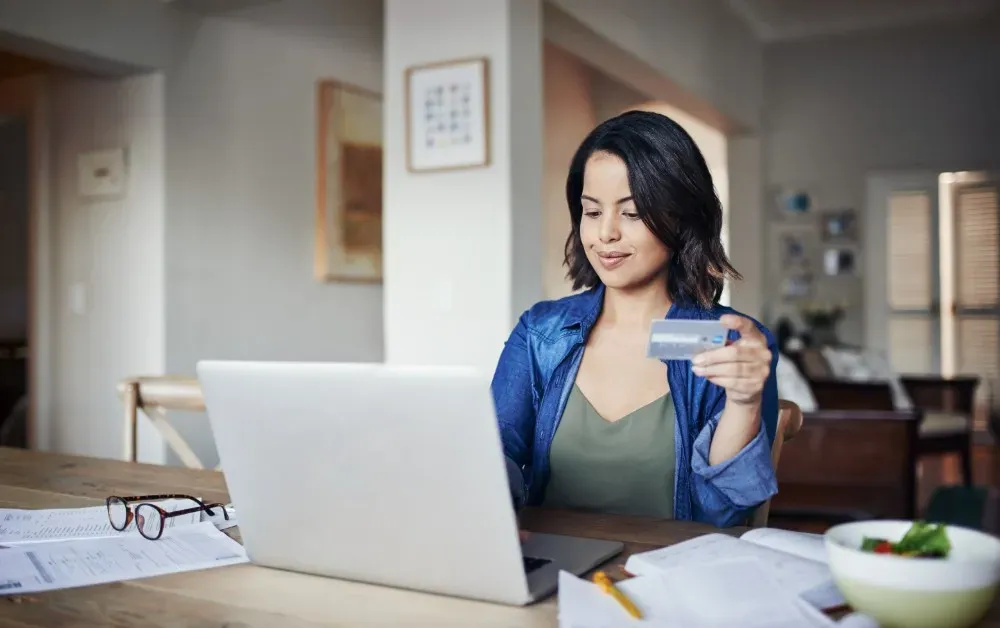 Image of a customer using credit card to purchase infront of a laptop
